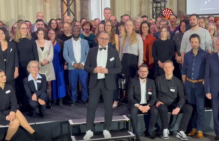 Prof. Dr. Thomas Auhuber steht vor einer großen Gruppe Absolventen