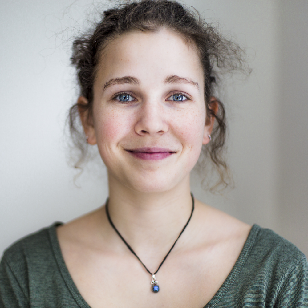 Porträt einer jungen Frau mit lockigem Haar und einem freundlichen Lächeln.