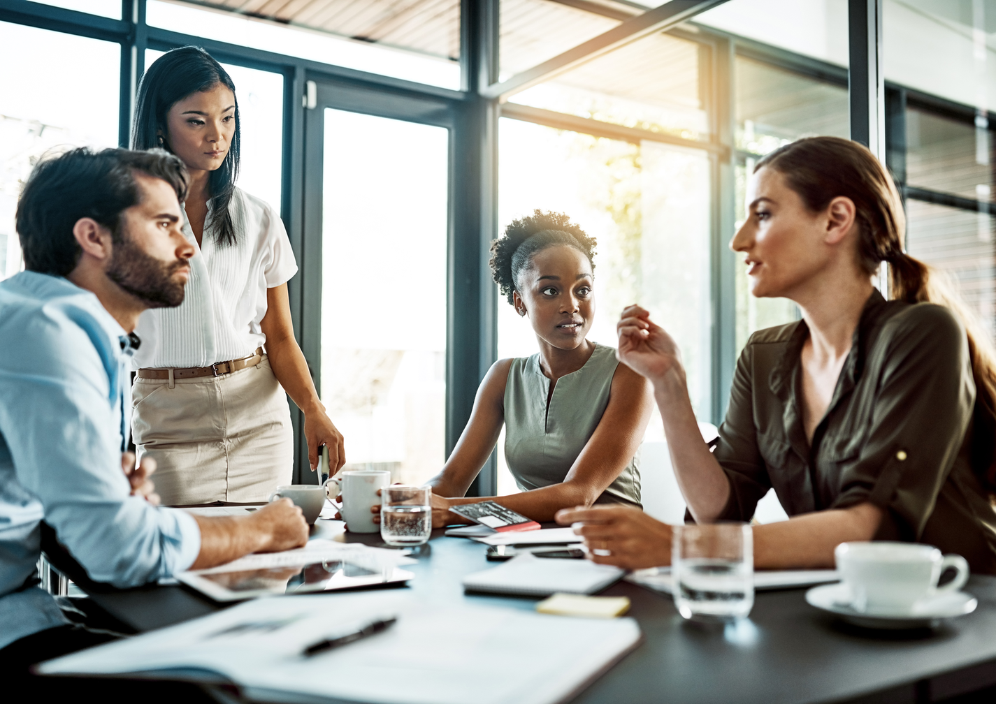 Vier Personen in einem modernen Büro sitzen um einen Tisch und diskutieren konzentriert bei einem Meeting.