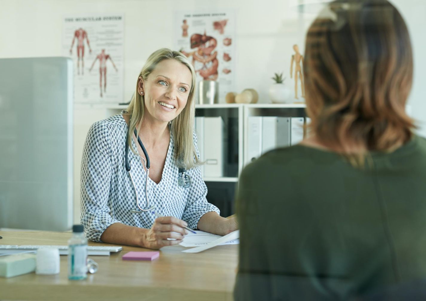Ärztin sitzt mit einer Frau am Tisch und führt ein Beratungsgespräch