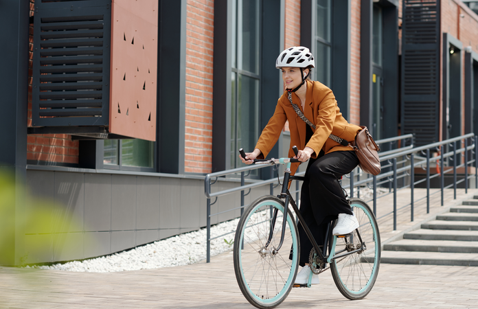 Eine Frau mit weißem Helm fährt ein schwarzes Fahrrad