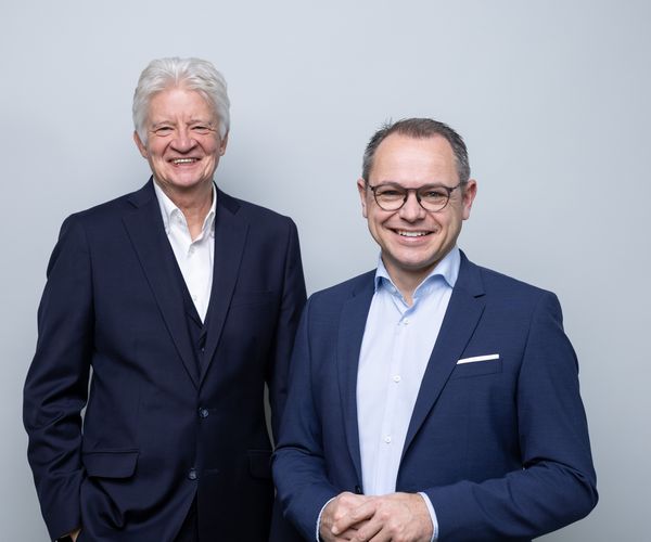 Bernd Werres und Thomas Auhuber Geschäftsführer von BG prevent stehen nebeneinander und lächeln in die Kamera.