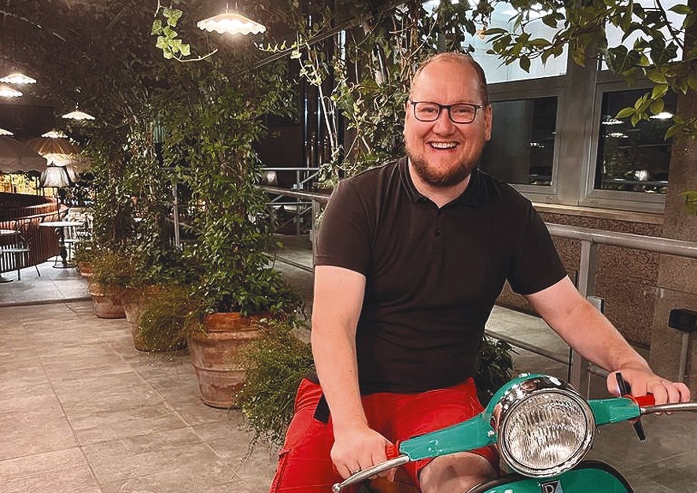 Stephan Anders-Krummnacker mit T-Shirt und jurzer Hose auf einer Piaggio Vespa