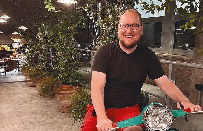 Stephan Anders-Krummnacker mit T-Shirt und jurzer Hose auf einer Piaggio Vespa